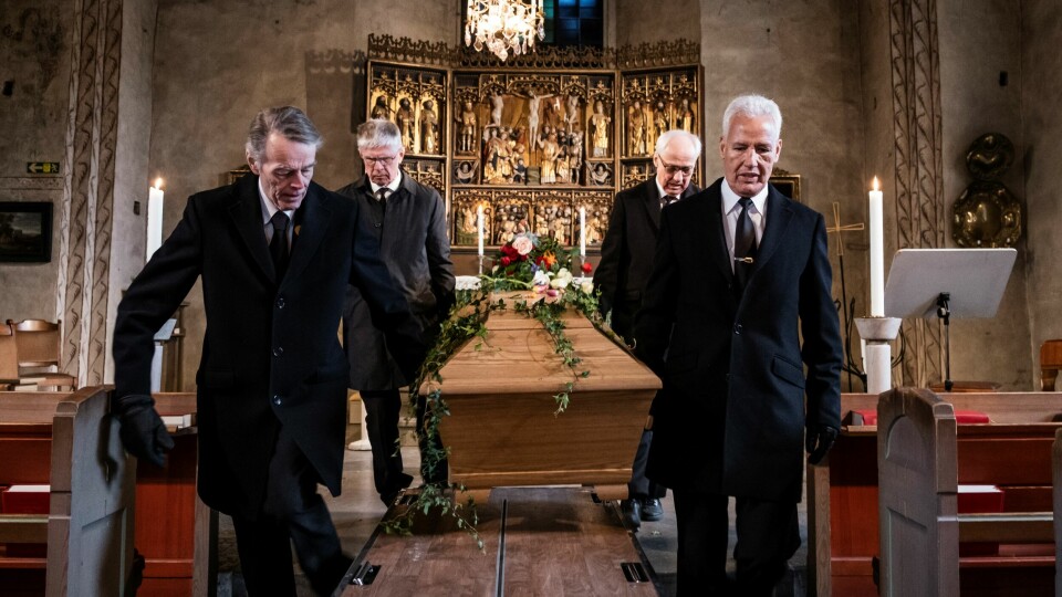 Ett kistbärarlag bär ut kistan efter en begravning. De är alla traditionellt klädda i svart kostym och svart slips, men så klär sig långt ifrån alla begravningsgäster i dag. kistbärarlag från täby församling bär ut kista från begravning. De har på sig svarta begravningskläder