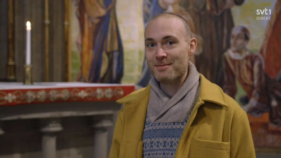 Jesper Rönndahl, programledare för Melodifestivalen 2023, framför altartavlan i Linköpings domkyrka.