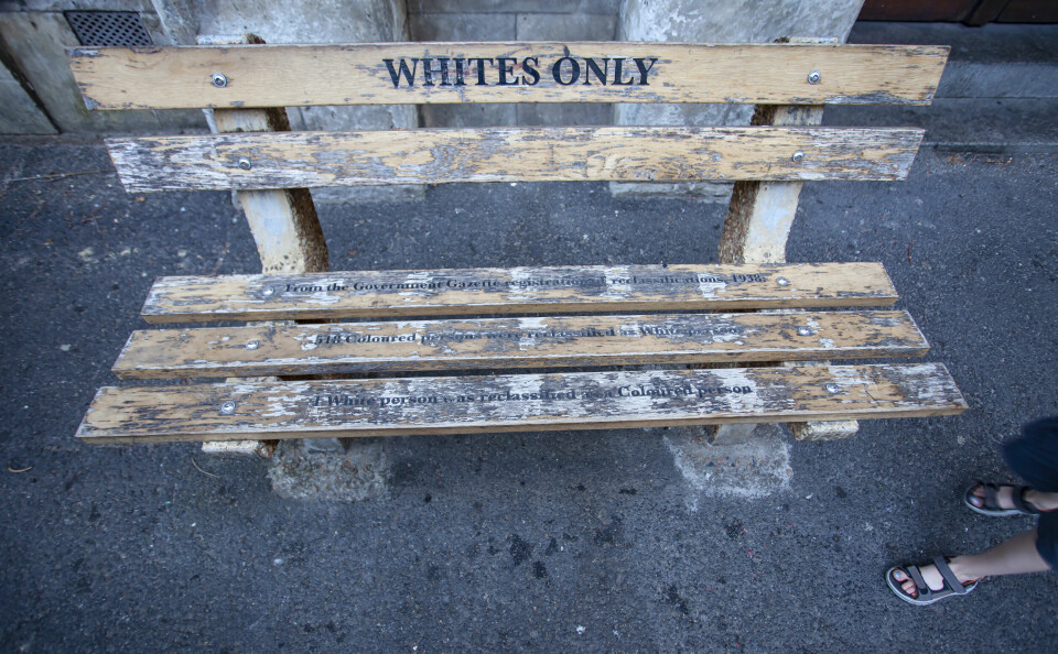 For 'whites only' - a bench in Cape town. Bench with the inscription, as the memory of apartheid and segregation in South Africa. Memorial bench and feet of a passing boy