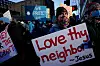 Person i folkmassa håller en skylt med texten ”Love thy neighbor – Jesus” vid en protest i Minneapolis.