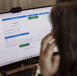 En person sitter vid en dator och tittar på en webbsida för lönesystemet Medvind.